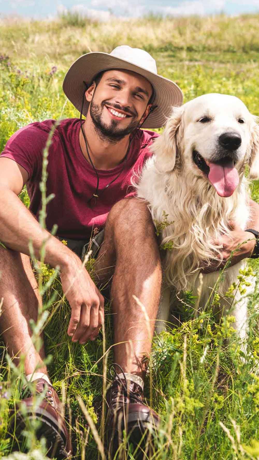 Mann mit seinem Hund in der Wiese sicher vor Zecken